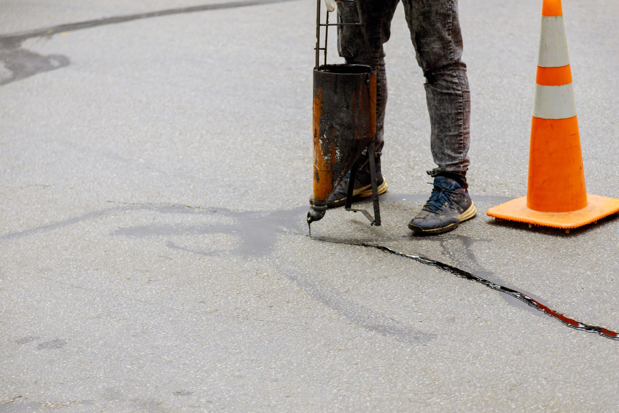 worker performs crack sealing with a machine